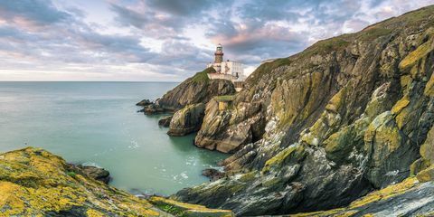 Faro de Baily, Howth, Condado de Dublín, Irlanda, Europa. Vista panorámica del acantilado y el faro al amanecer.