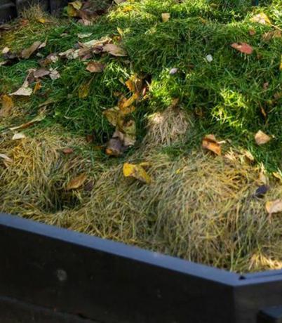 Haciendo compost en un contenedor de compostaje en un pequeño jardín.