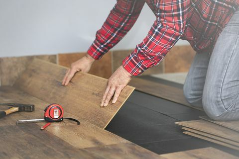 manos de los trabajadores instalando suelo laminado de madera en la habitación