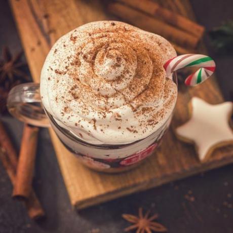 taza de chocolate caliente con crema batida y bastón de caramelo en un acogedor ambiente navideño