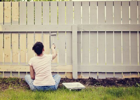 Mujer sentada en la valla de pintura del piso del jardín