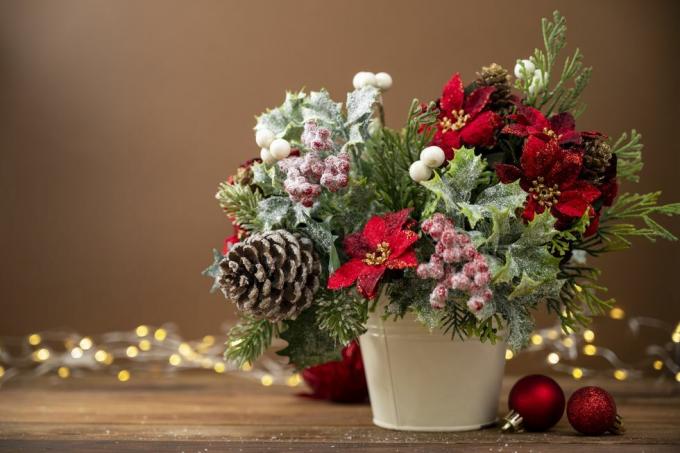 arreglo festivo navideño con flor de pascua roja sobre fondo marrón con luces bokeh