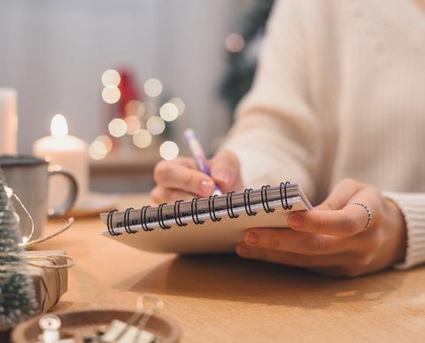 planes de metas que hacer y lista de deseos para el concepto de navidad de año nuevo escribiendo en el cuaderno mujer mano sujetando el bolígrafo en el bloc de notas en casa en vacaciones de invierno navidad