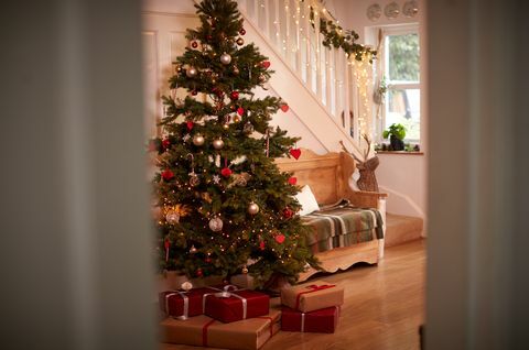 Pasillo del hogar decorado para Navidad con árbol y regalos vistos a través de la puerta abierta