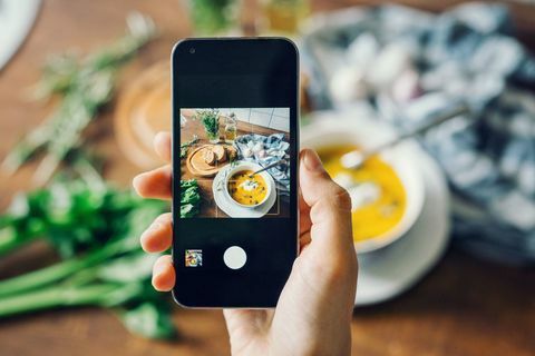 Foto de mujer tomando sopa de calabaza con smartphone