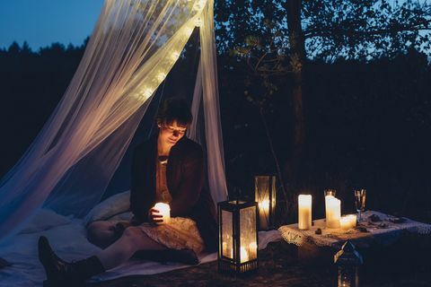 Mujer feliz en naturaleza otoñal a la luz de las velas