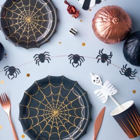 Platos de fiesta de Halloween decorados con una telaraña adornada con papel de cobre brillante.