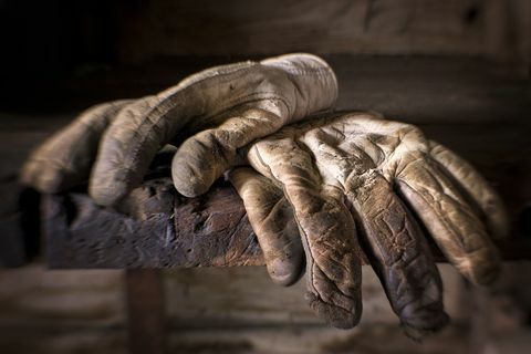 Guantes de trabajo bien gastados, sucios y aceitosos encima de un viejo banco de trabajo.