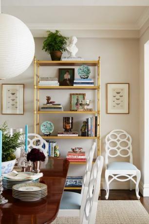 mesa de comedor de madera, sillas blancas y azules, librería dorada