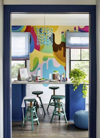 sala de juegos para niños con taburetes y materiales de arte sobre una mesa alta