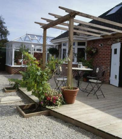 Patio cubierto con mesa y sillas bajo pérgola