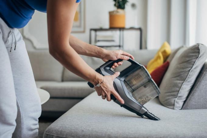 Mujer aspirando la sala de estar con aspiradora inalámbrica.