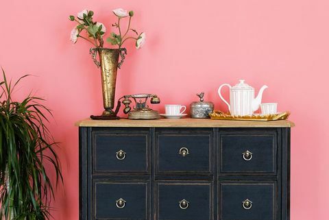 una vieja cómoda con objetos en el fondo de una pared rosa al lado hay una flor en una maceta hermoso interior de estilo antiguo