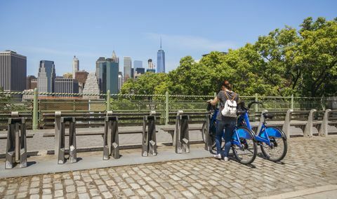 Mujer tomando una bicicleta frente al horizonte de Manhattan en la ciudad de Nueva York