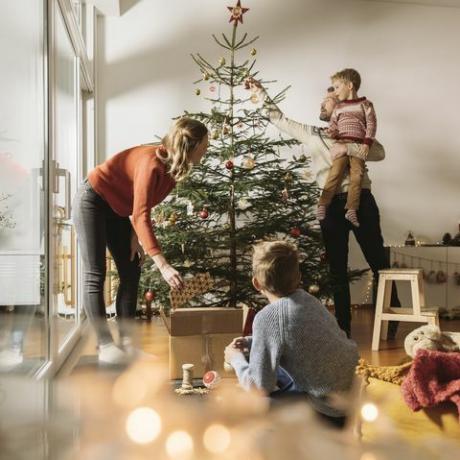 familia de cuatro decorando su árbol de navidad