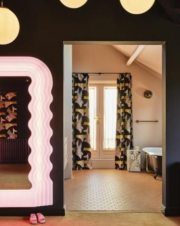 baño en suite cortinas a juego, una puerta abierta y un esquema de color caramelo apagado unen las dos habitaciones espejo vintage ettore sottsass azulejos winckelmans