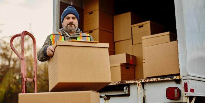 Trabajador descargando cajas de cartón desde una furgoneta de reparto