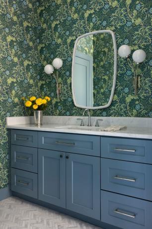 cuarto de baño con armario azul y papel tapiz floral verde