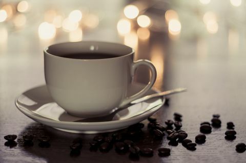 La taza y el platillo que contenía café estaban sentados en una mesa salpicada de granos de café.