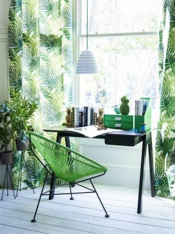 moderna oficina en casa y área de estudio con cortinas de hojas verdes vibrantes, sillas verdes de estilo retro en el escritorio negro, lámpara colgante con pantalla blanca, tarimas, jardineras, archivos, escritorio, frente a la ventana, luz, década de 1960, tropical colores,
