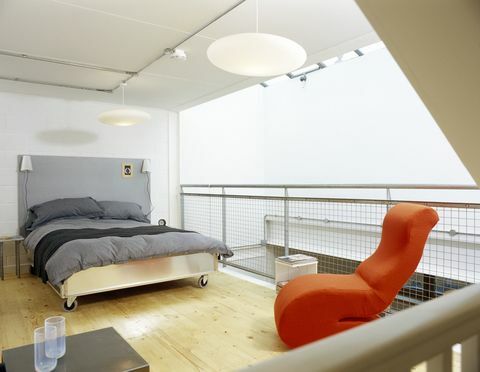 Dormitorio moderno con funda nórdica gris y silla naranja brillante