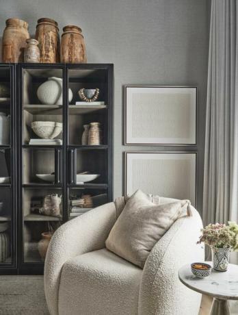 sillón blanco, librería negra, jarrones de madera