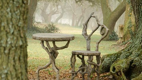 Una imagen de una silla y una mesa de imitación bois entre árboles en un día brumoso