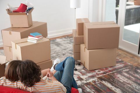 Vista trasera de la pareja en silla roja en casa con cajas de cartón