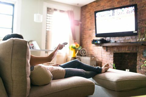 Mujer relajante en línea en el sofá leyendo algunos papeles