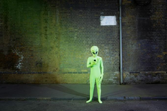 hombre vestido con traje de extraterrestre mirando el móvil