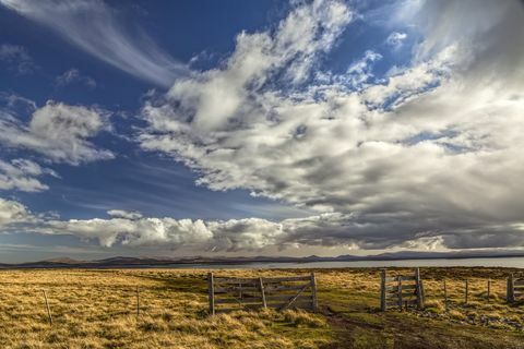 Valla y nubes en la tarde la luz, isla de guijarros, islas Malvinas