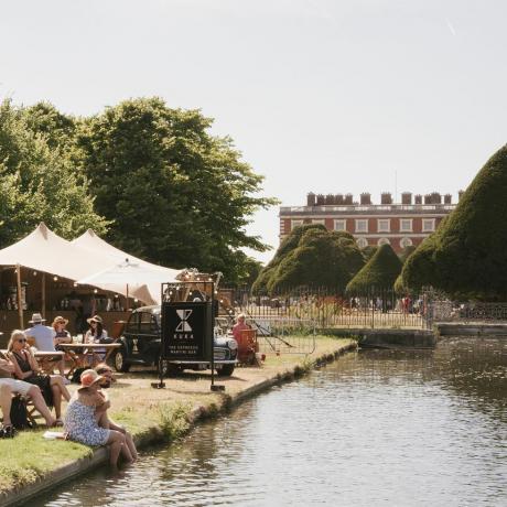 los visitantes se relajan en el kuka bar junto al agua larga en el rhs hampton court palace garden festival 2022