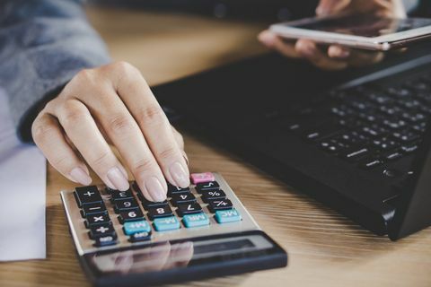 Mujer mano calculando mientras trabajaba en la computadora portátil