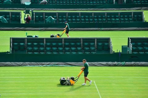 El personal de tierra corta el césped en una cancha en el All England Lawn Tennis Club en Wimbledon