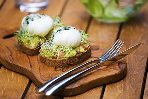 Rebanadas de pan tostado con puré de aguacate, huevo cocido y brotes