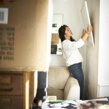 Mujer tomando una foto de la pared lista para empacar mientras se muda de casa