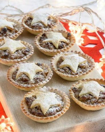 Tartas de carne picada al horno para Navidad en pizarra con agujas de pino y decoraciones