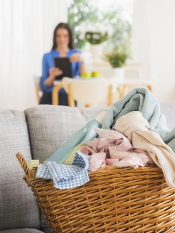 Cesto de la ropa en el sofá y la mujer en el fondo